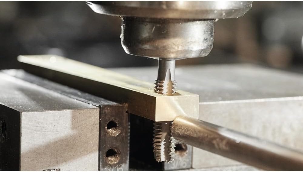 A close-up macro action shot of a Bosch tap cutting threads into a pre-drilled hole in a brass bar.