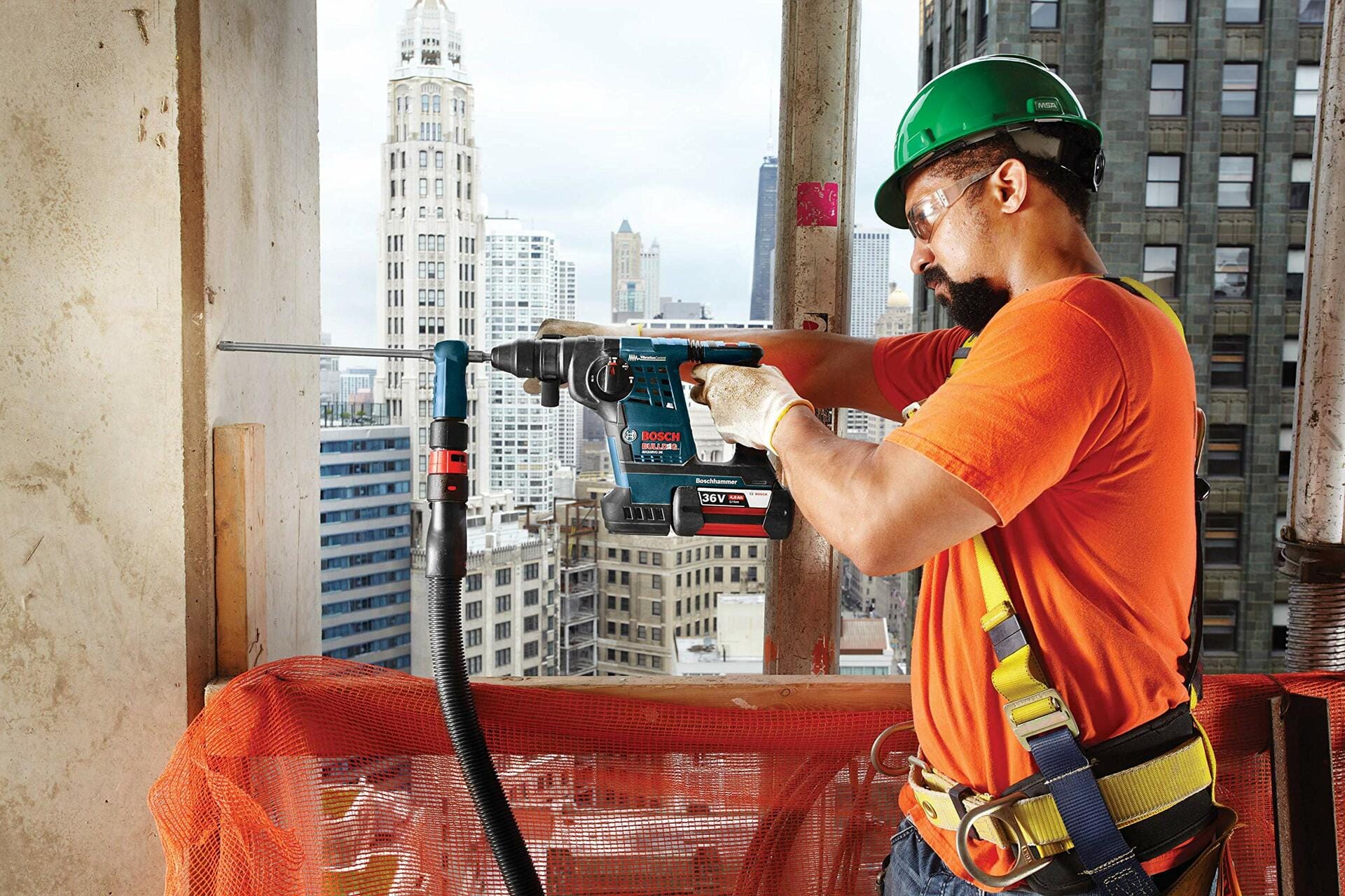 Construction worker using Bosch rotary hammer drill with dust extractor on high-rise site; city skyline visible in background.