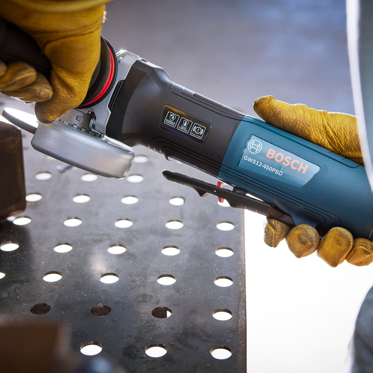 Cutting steel conduit clamped in a bench vise using the Bosch 4-1/2-inch paddle switch angle grinder.
