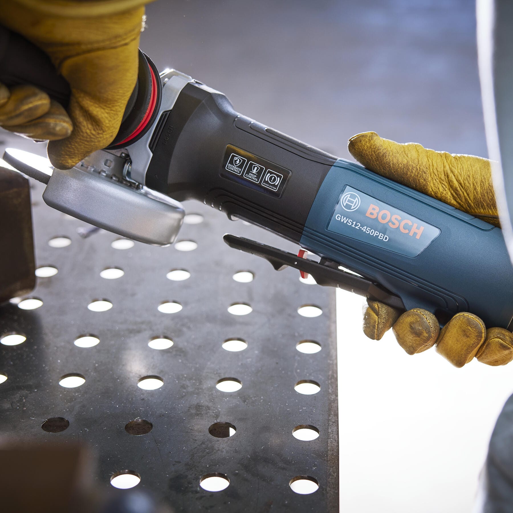 Cutting steel conduit clamped in a bench vise using the Bosch 4-1/2-inch paddle switch angle grinder.