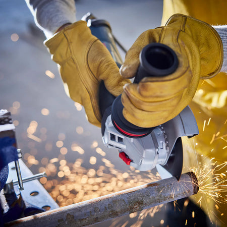 Operator adjusting the rear variable speed dial on the Bosch GWS12-450PBD angle grinder housing.