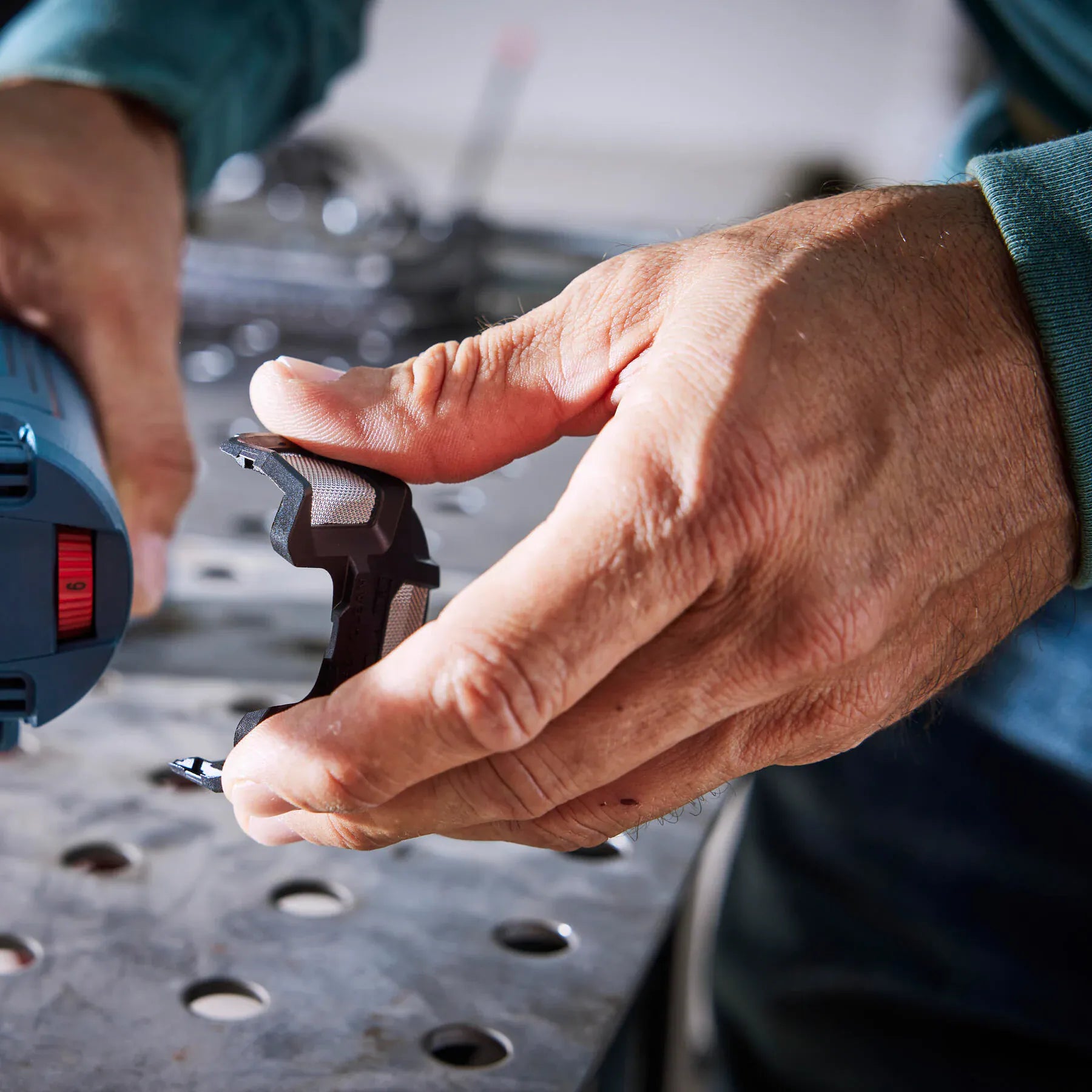 Removing the snap-on air intake dust filter screen from the Bosch angle grinder for routine cleaning.