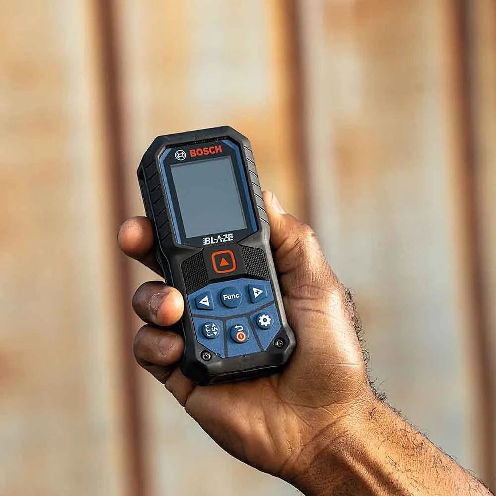 Close-up action shot of a hand holding the Bosch BLAZE GLM165-27C laser measure, highlighting the compact size, rugged rubber overmold housing, and color display interface