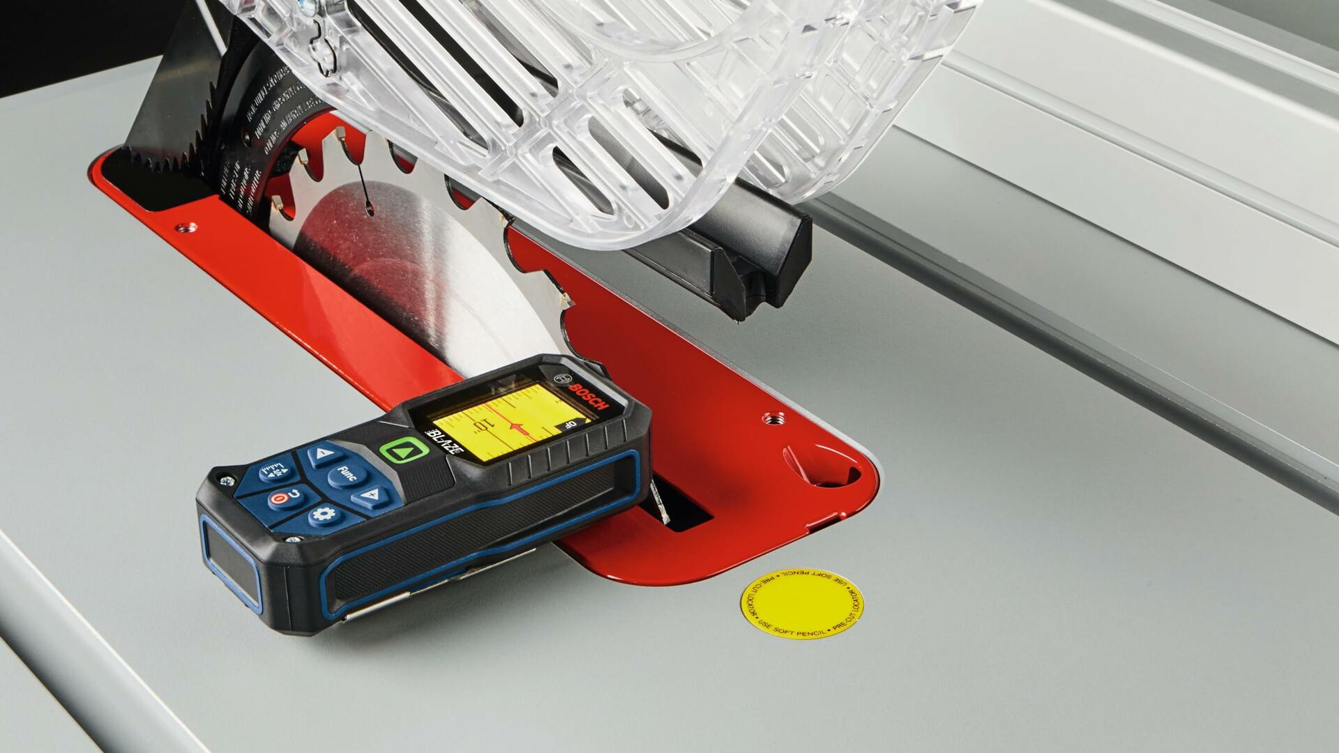 Close-up shot of the laser measure placed on a table saw surface, demonstrating the inclinometer function used to verify or measure the blade angle or table flatness