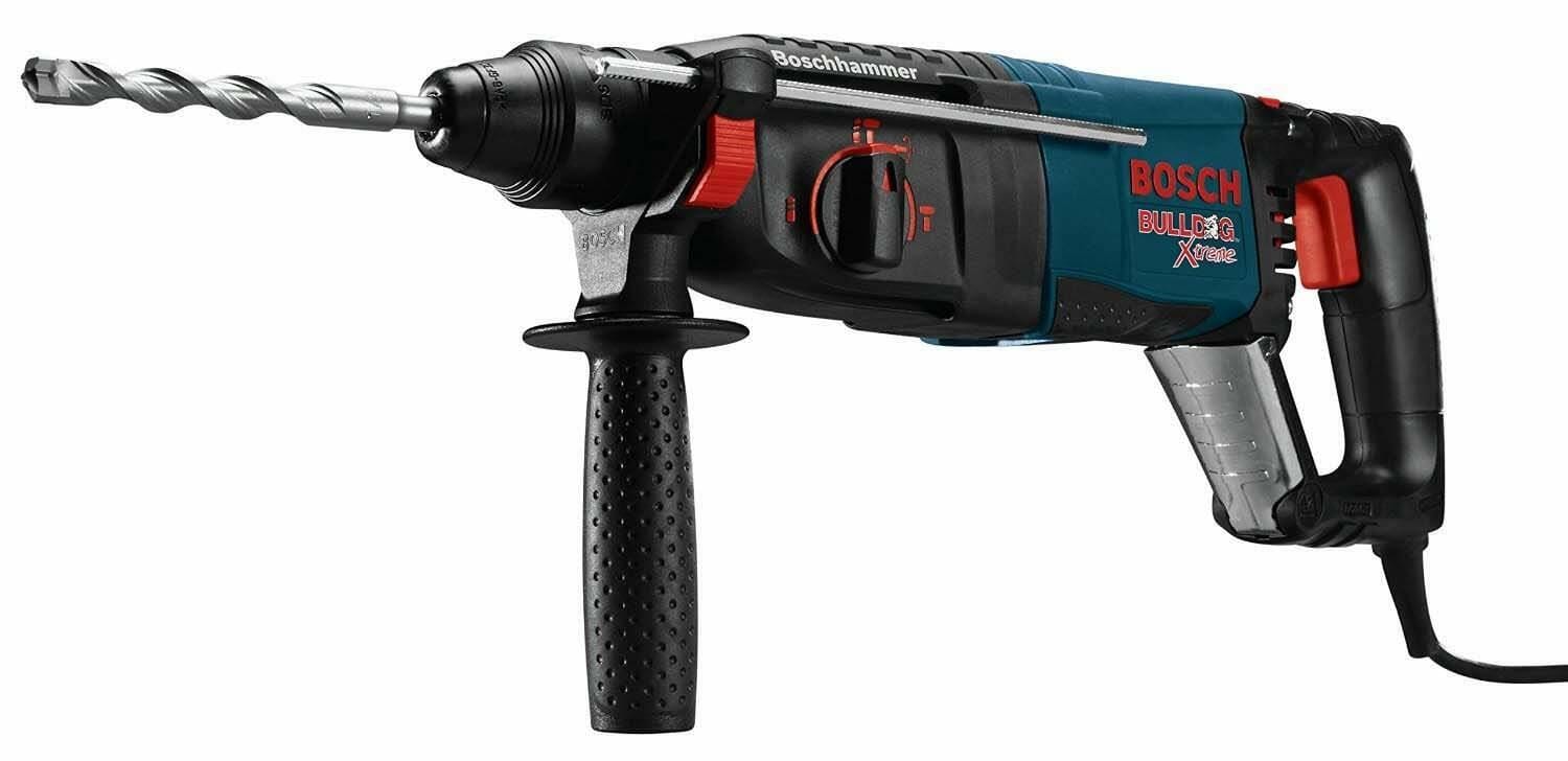 A three-quarter profile view of the Bosch Bulldog Xtreme rotary hammer, showing the D-handle, auxiliary handle, and an SDS-plus bit inserted into the chuck.