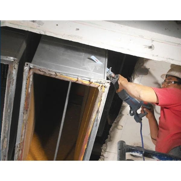 Action shot of a construction worker using the blade to cut through overhead metal HVAC ductwork during a renovation.