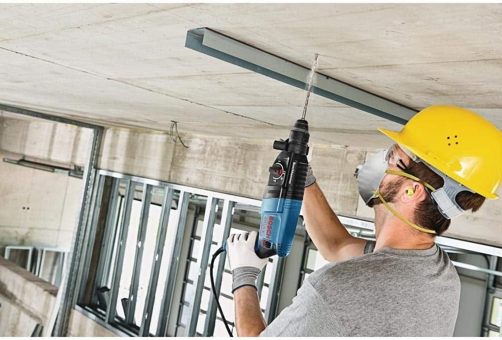 Action shot of a professional contractor using the rotary hammer to drill vertically into a concrete ceiling structure.