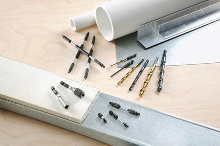 An application studio layout display showing loose Bosch hex shank drill bits, long driver bits, and socket adapters scattered on a wooden work surface alongside construction materials like white PVC pipes, aluminum L-channel beams, and a sheet metal plate.