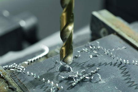 An action photograph showing a Bosch cobalt drill bit penetrating a thick metal plate, creating long metal shavings to demonstrate its high-speed material removal.