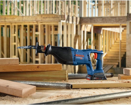 The Bosch 18V reciprocating saw sitting upright on a construction site with lumber and metal pipes in the background.