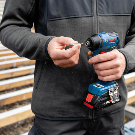 Worker inserting a hex bit one-handed into the quick-change collet of the Bosch GDR18V-1950C impact driver.