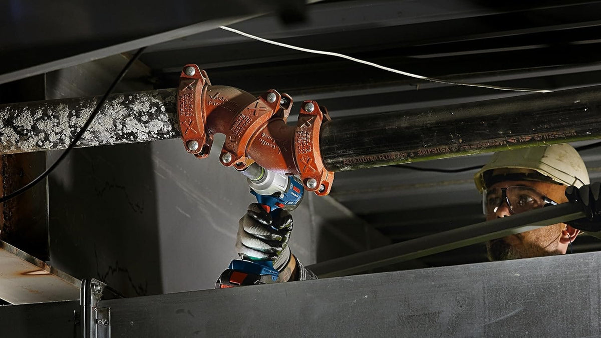 Tradesperson securing overhead grooved pipe coupling bolts on a fire sprinkler line using the Bosch GDS18V-330PC.