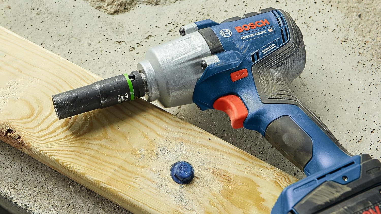 Bosch GDS18V-330PC resting on structural framing timber beside a driven blue heavy-duty concrete anchor screw.