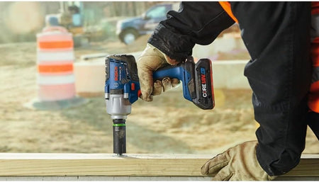 Contractor driving a large timber lag bolt vertically into framing lumber using the Bosch 18V mid-torque impact wrench.