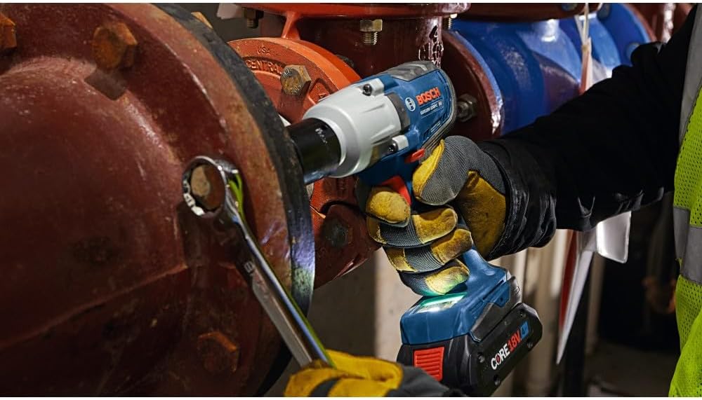 Industrial pipefitter fastening high-torque flange bolts in low light using the Bosch GDS18V-330PC impact wrench.