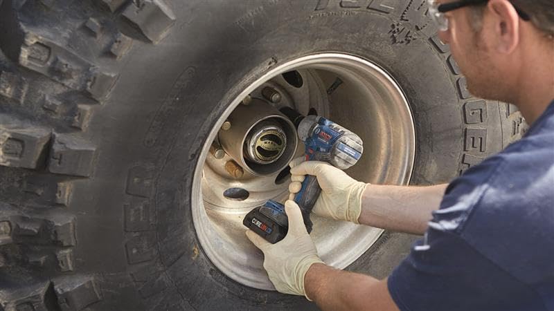 Automotive technician busting stubborn wheel fasteners on an off-road truck tire with the Bosch 18V impact wrench.
