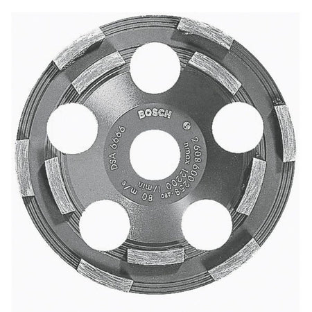 A studio display shot of the Bosch DC500 5-inch double row segmented diamond cup wheel against a white background, clearly illustrating its unthreaded 7/8-inch center arbor hole, six large round airflow cooling ports, and its abrasive diamond-embedded double row grinding segments engineered for low working temperatures and efficient coating removal.