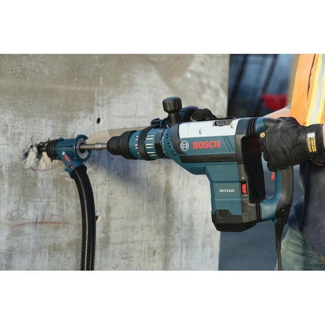 An action shot of the Bosch DH712VC hammer being used with an HDC300 dust collection attachment to chisel a concrete wall.