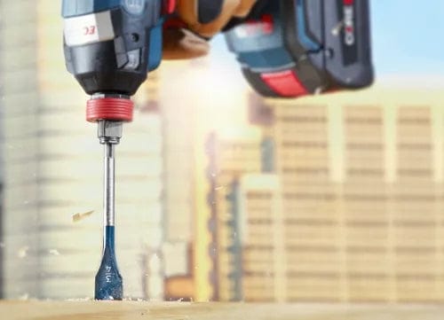 Close-up action shot of a Bosch Daredevil spade bit drilling vertically into wood creating wood chips.