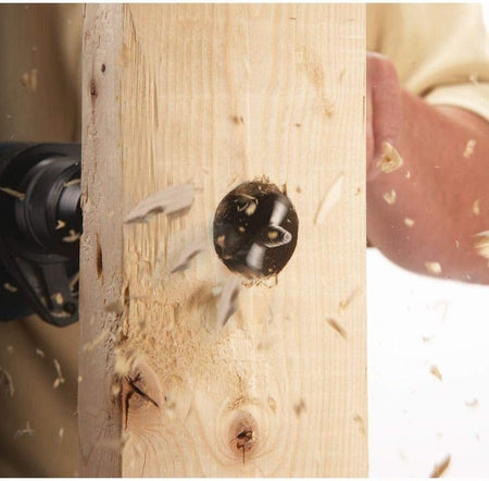 Close-up action shot showing wood chips flying as the spade bit rapidly drills through a piece of lumber.