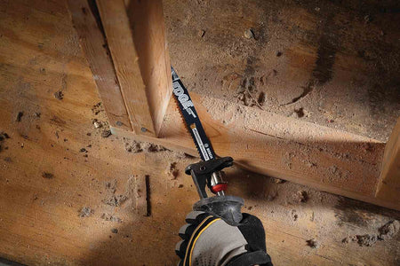Action shot of a reciprocating saw equipped with a Bosch Edge blade cutting through the wooden base plate of a wall frame during demolition.