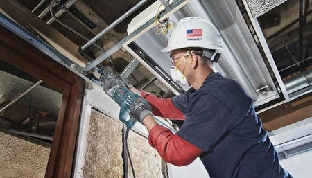 Low angle action shot of a worker using the blade to cut through overhead metal door framing during a renovation project.