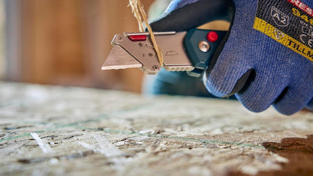 Close-up detail of the integrated strap cutter notch being used to cut a piece of twine without deploying the main utility blade.