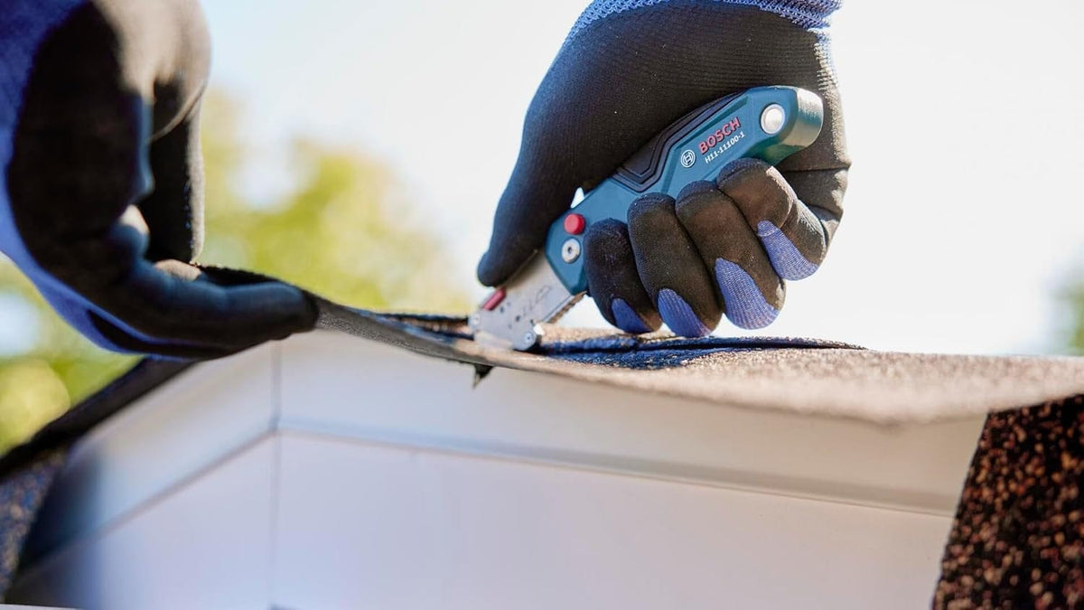 Lifestyle view of a professional cutting roofing material with the Bosch utility knife, showcasing its durability in tough applications.