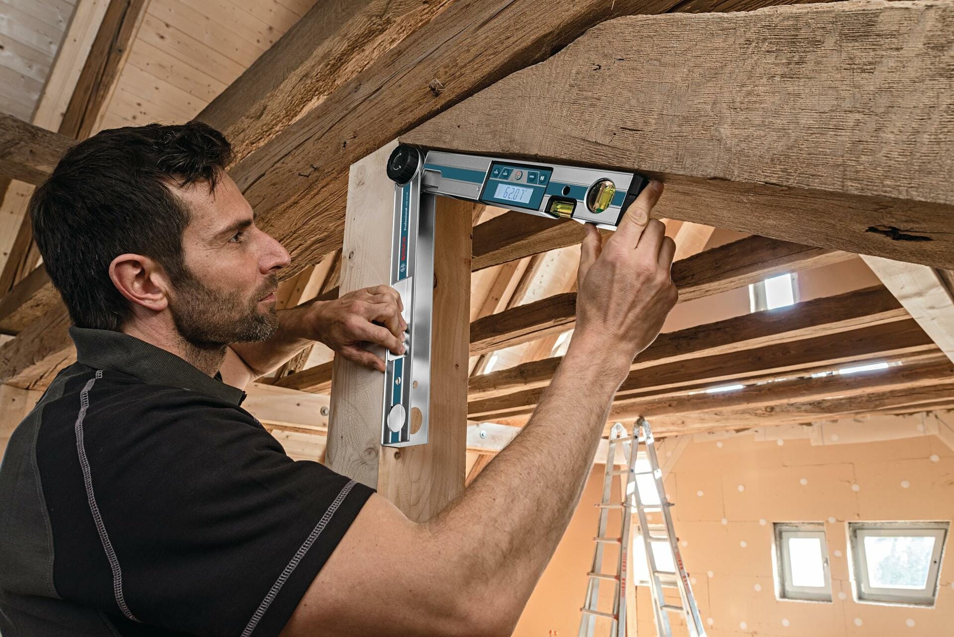Construction worker measuring the angle between a wooden post and an overhead beam using the Bosch GAM 220 MF digital angle finder