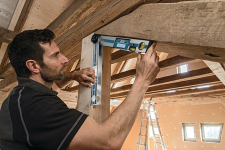 Construction worker measuring the angle between a wooden post and an overhead beam using the Bosch GAM 220 MF digital angle finder