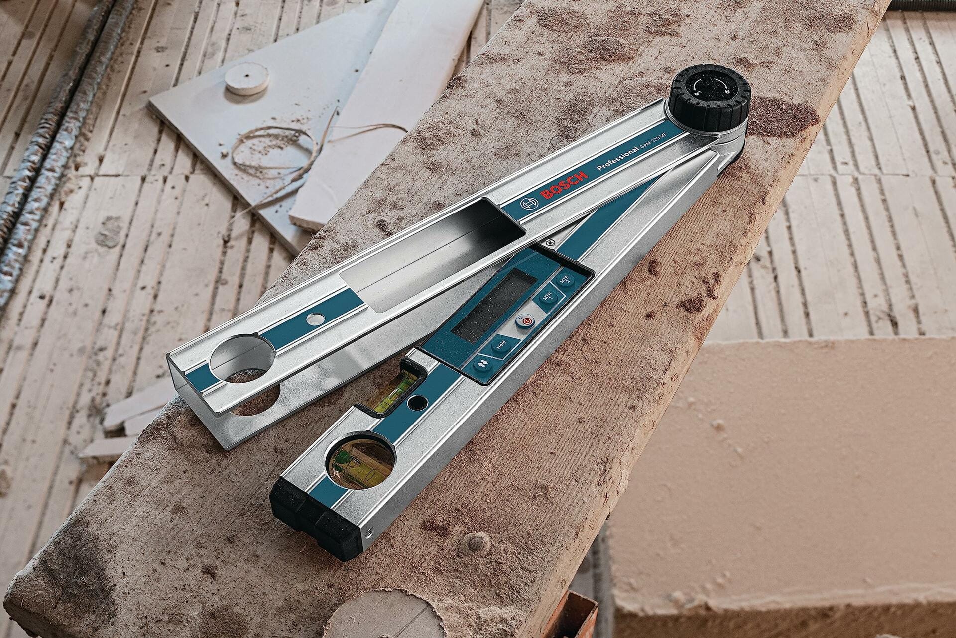 Overhead close-up of the Bosch GAM 220 MF digital angle finder opened to measure an angle, resting on rough construction lumber