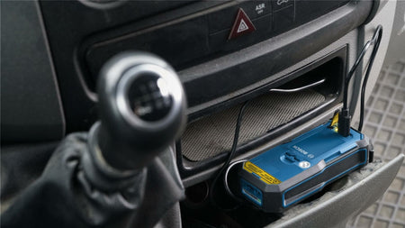Action shot showing the laser measure charging via its USB-C port in a vehicle, demonstrating the flexibility of charging the GBA37V10 battery using car adapters on the jobsite