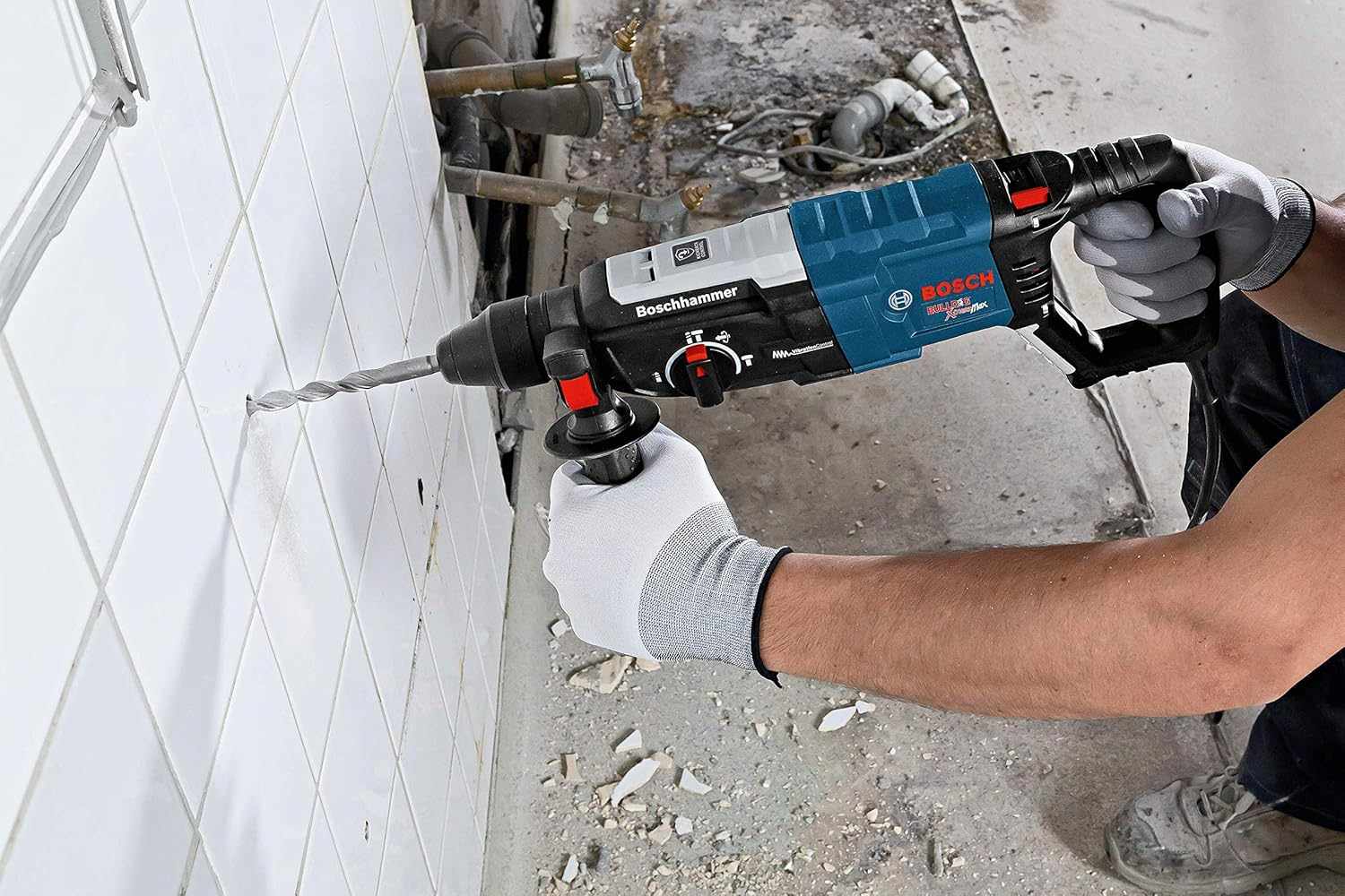 Close-up view of the Bosch SDS-plus rotary hammer drilling into a white tiled wall, showing the precision of the hammer drill for masonry and remodeling work.