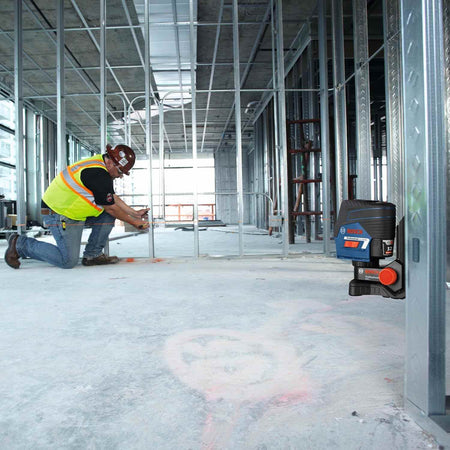 The Bosch GCL100-80C laser level mounted to a steel stud using its magnetic base, projecting a level horizontal line for electrical box installation.