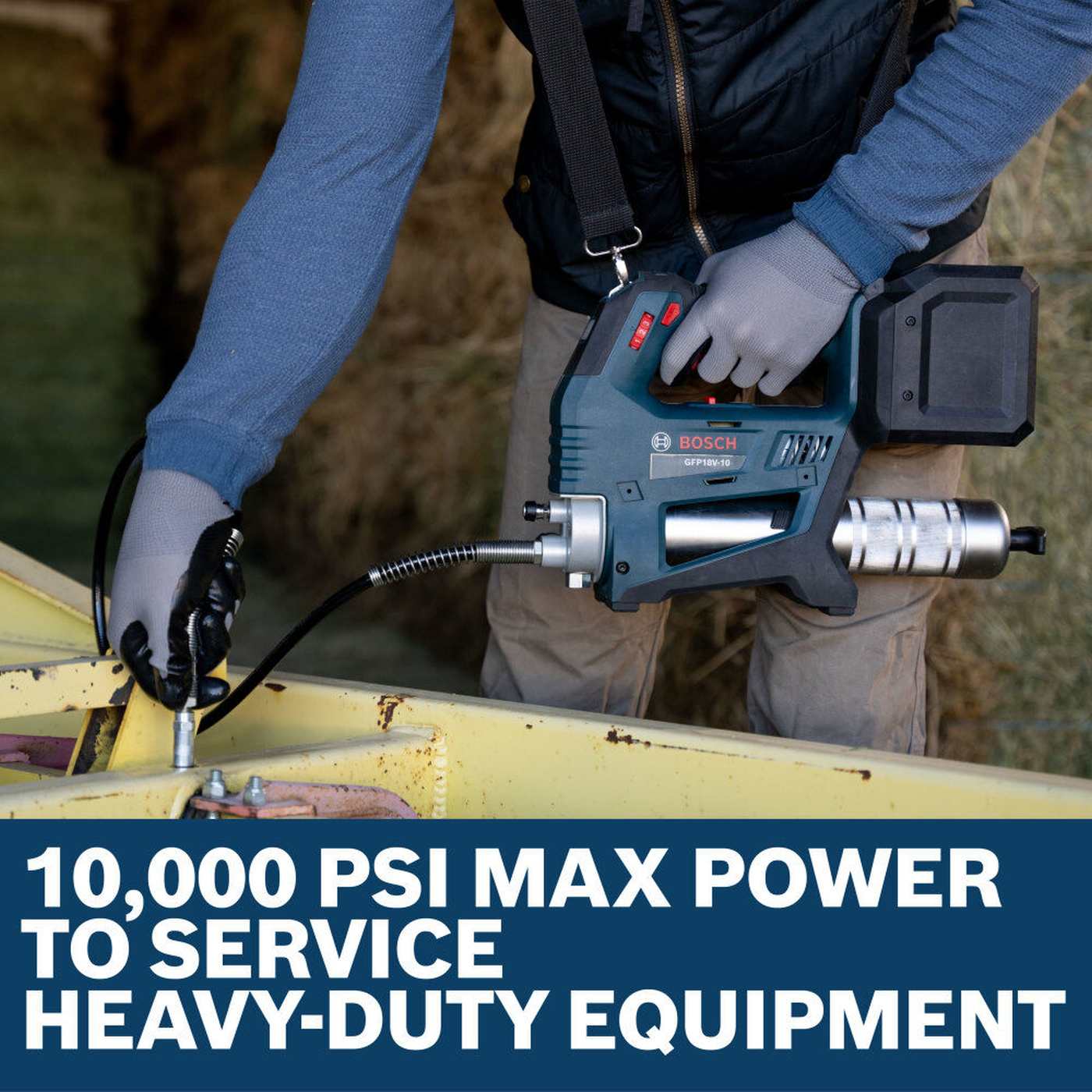 An action shot of a technician using the Bosch 18V grease gun to service heavy-duty yellow construction equipment, emphasizing the 10,000 PSI maximum power rating for commercial maintenance.