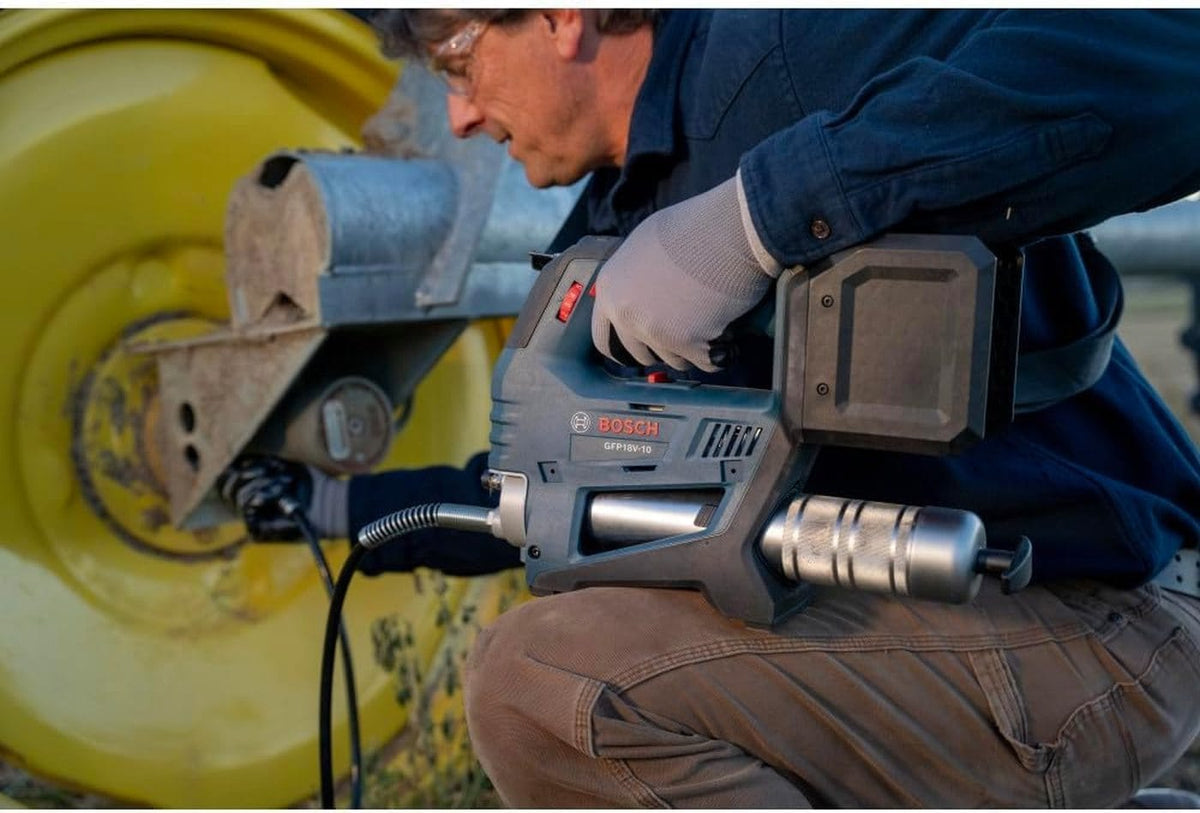 A field maintenance shot showing an operator applying grease to a tractor hub with the Bosch 18V brushless tool, emphasizing its portability and high-pressure performance for agricultural machinery.