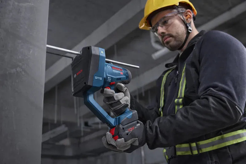 A real-world application view identical to file GGC18V-12N 3.jpg capturing a mechanical installation technician using the Bosch GGC18V-12N brushless threaded rod cutter inside a building framework. This graphic-free variant highlights the lightweight balanced ergonomics of the handheld tool as it executes a spark-free, burr-free cut through a structural concrete anchor rod.
