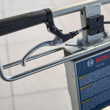 Close-up of the metal hand brake lever located on the handle bar for controlling the cart's movement.