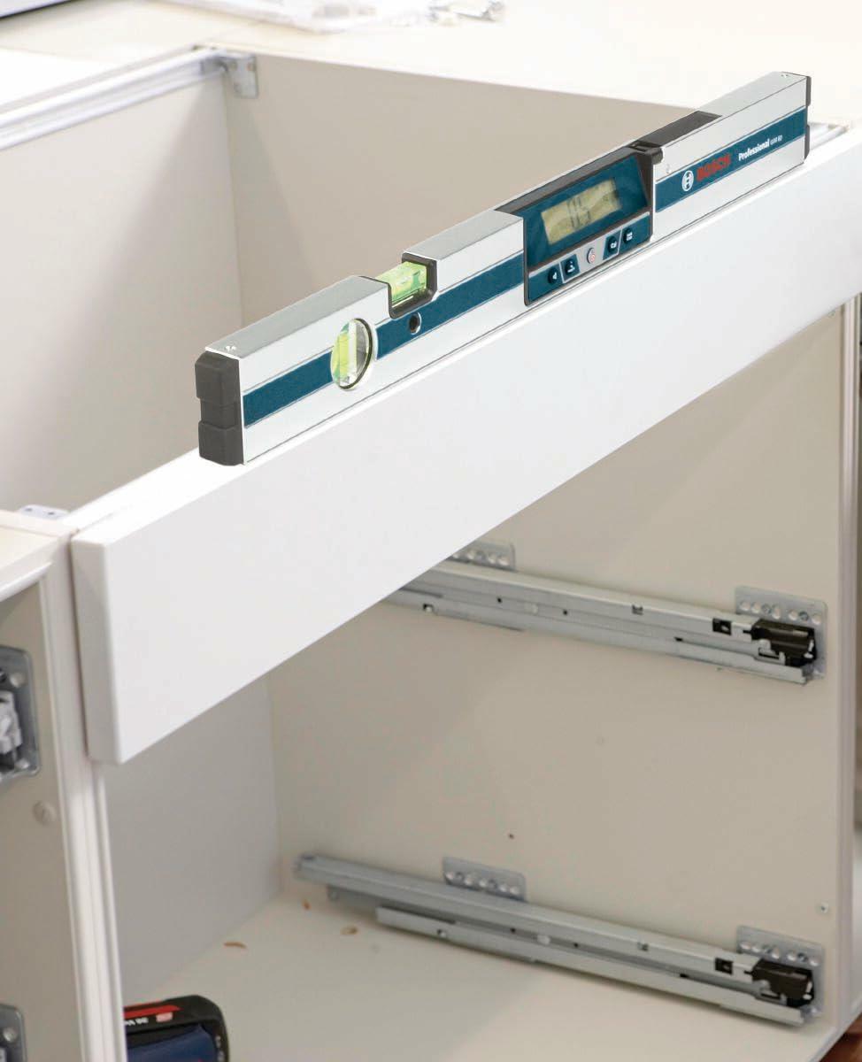 Close-up application shot showing the Bosch GIM60 digital level placed on the top rail of a cabinet, checking the horizontal alignment