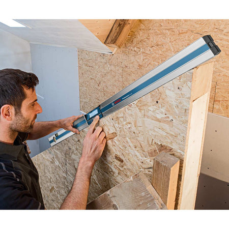 Person using Bosch digital level to measure angle between OSB panel and vertical beam in carpentry setting.
