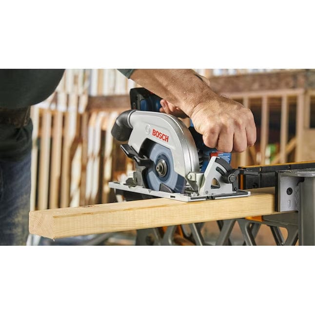 Person operating Bosch circular saw on workbench; lumber positioned for cutting in construction or workshop setting.
