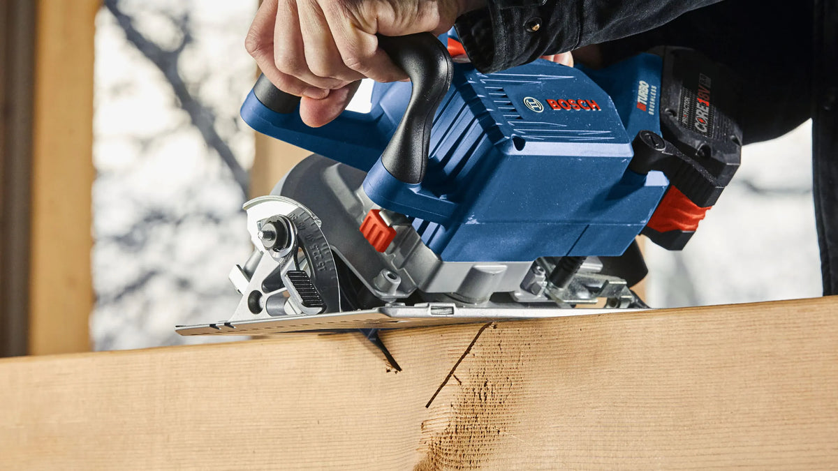 A close-up side angle application photo emphasizing the bevel cutting capability of the Bosch cordless circular saw, demonstrating the tool locked at an incline angle while cleanly carving a deep miter groove straight into the corner edge of a framing joist.