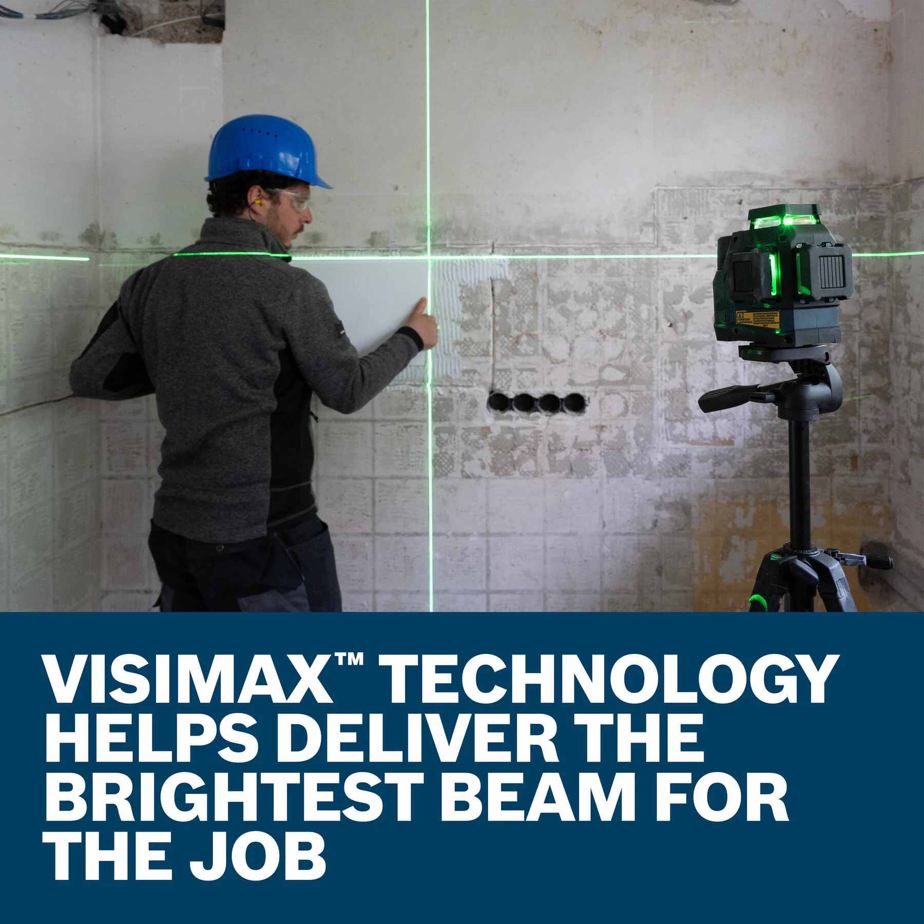A construction worker installing white wall tiles using a tripod-mounted green laser level for alignment, with an overlay text graphic that reads Visimax Technology helps deliver the brightest beam for the job.