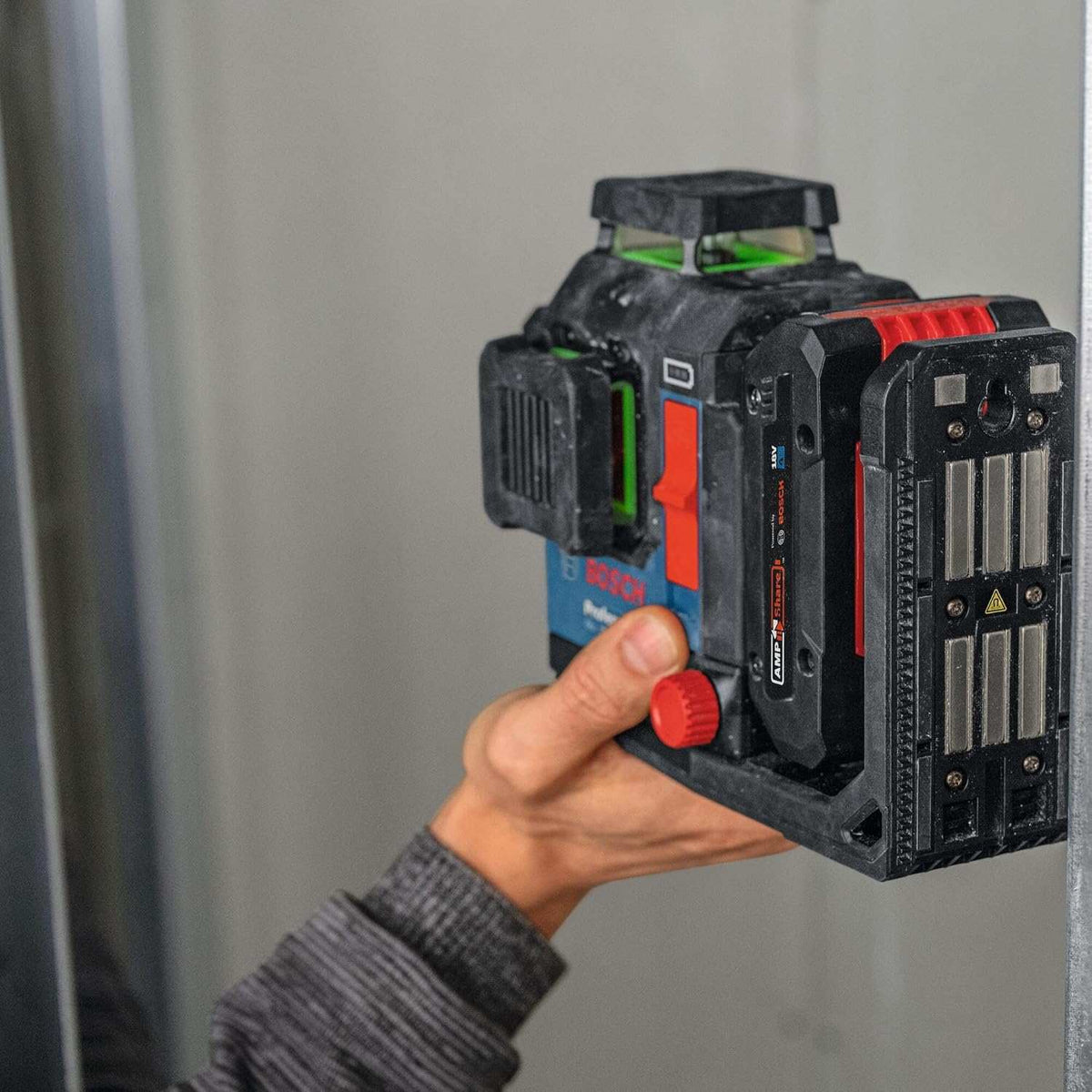 A hand positioning the laser level against a metal stud to demonstrate the strong integrated magnetic mount