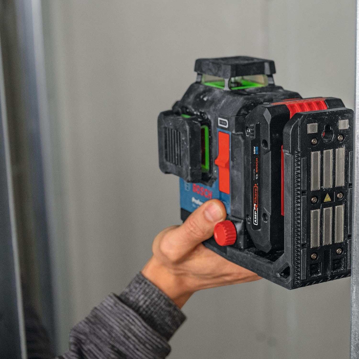 A hand positioning the laser level against a metal stud to demonstrate the strong integrated magnetic mount
