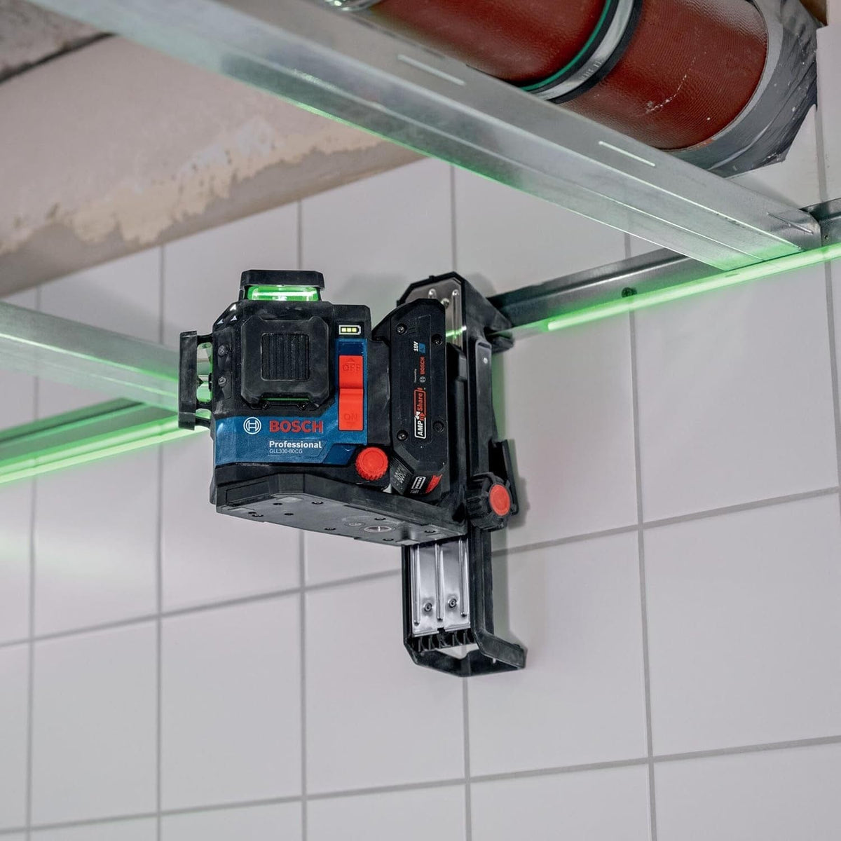 The laser level magnetically attached to a metal ceiling track and projecting a bright green horizontal line