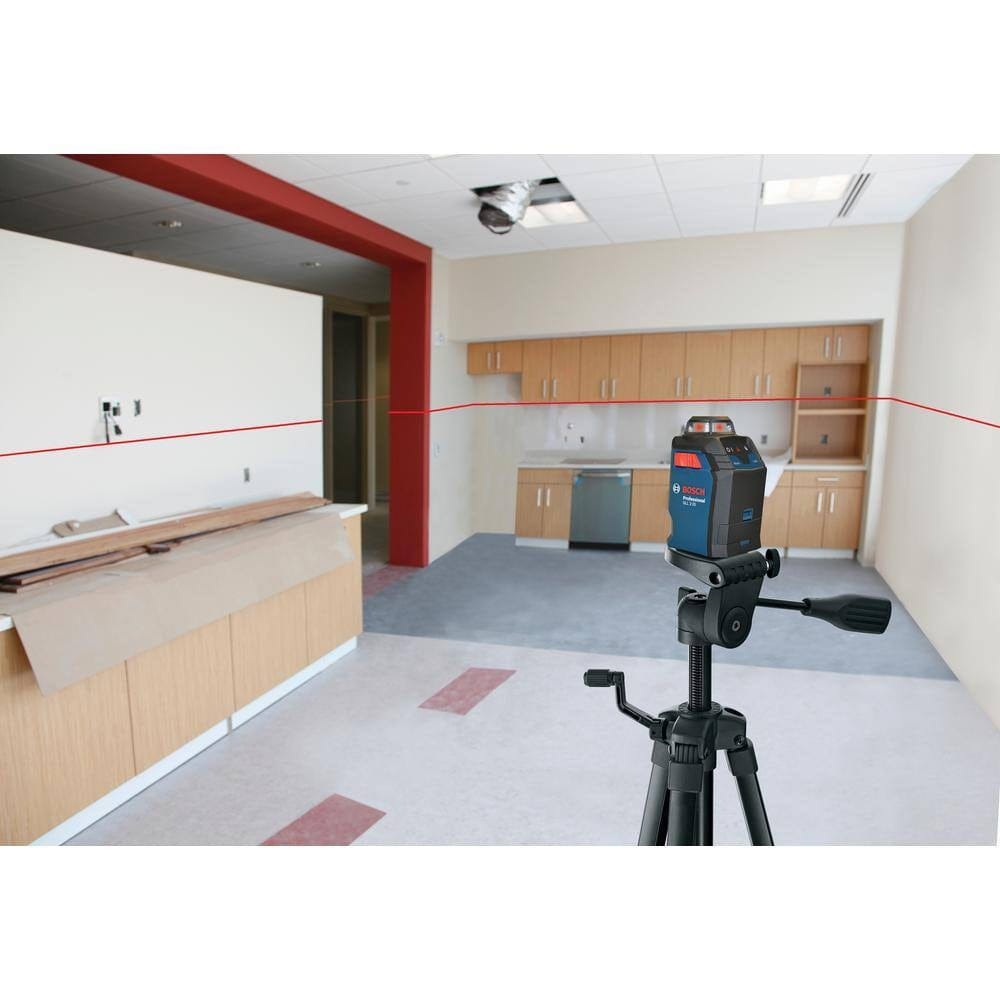 The Bosch GLL 2-20 laser level mounted on a tripod in a room under construction, projecting a continuous red horizontal level line across all four walls and cabinetry.