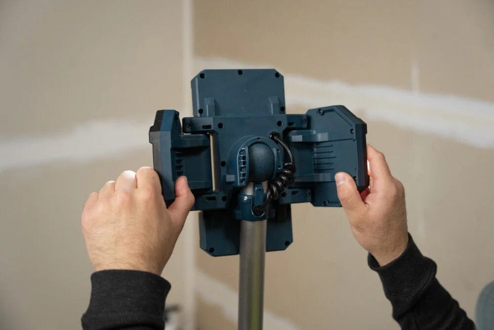 A close-up view of a worker's hands adjusting the individually swiveling side panels on the back of the 5,000-lumen LED light head.