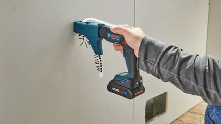 Bosch GTB18V-45 screwgun with GMA22 attachment driving collated screws into drywall. Operator presses tool against panel during installation. CORE18V battery visible on tool.