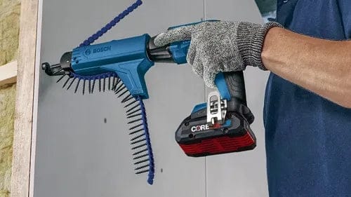Person using Bosch GTB18V-45 screwgun with GMA22 auto-feed attachment to fasten screws into drywall. Tool features collated screw strip and CORE18V battery for cordless operation.